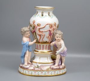 Restauration an Ziervase ca. um 1860. Fehlender Hand von Putto wurde nachmodelliert, angebracht und farblich angepasst. Anschliessend mit Glasur Versehen.